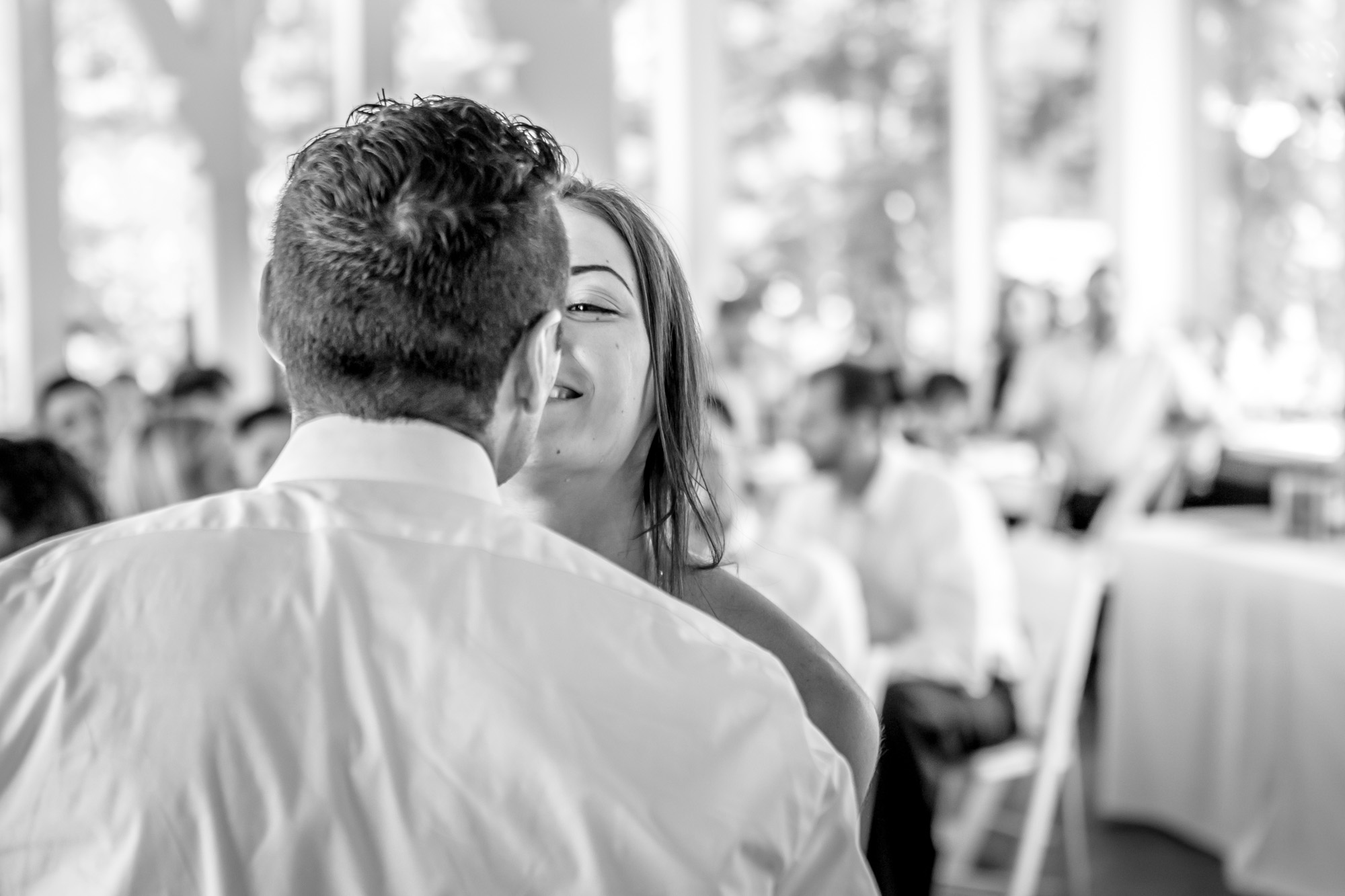 Bride smiling at groom in a candid black and white wedding reception photo