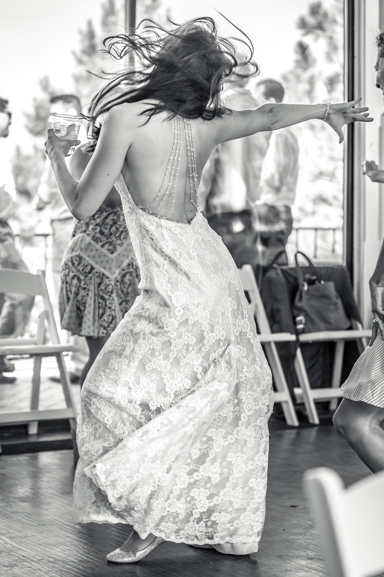 Bride dancing in a lace wedding dress at a reception, captured in black and white.