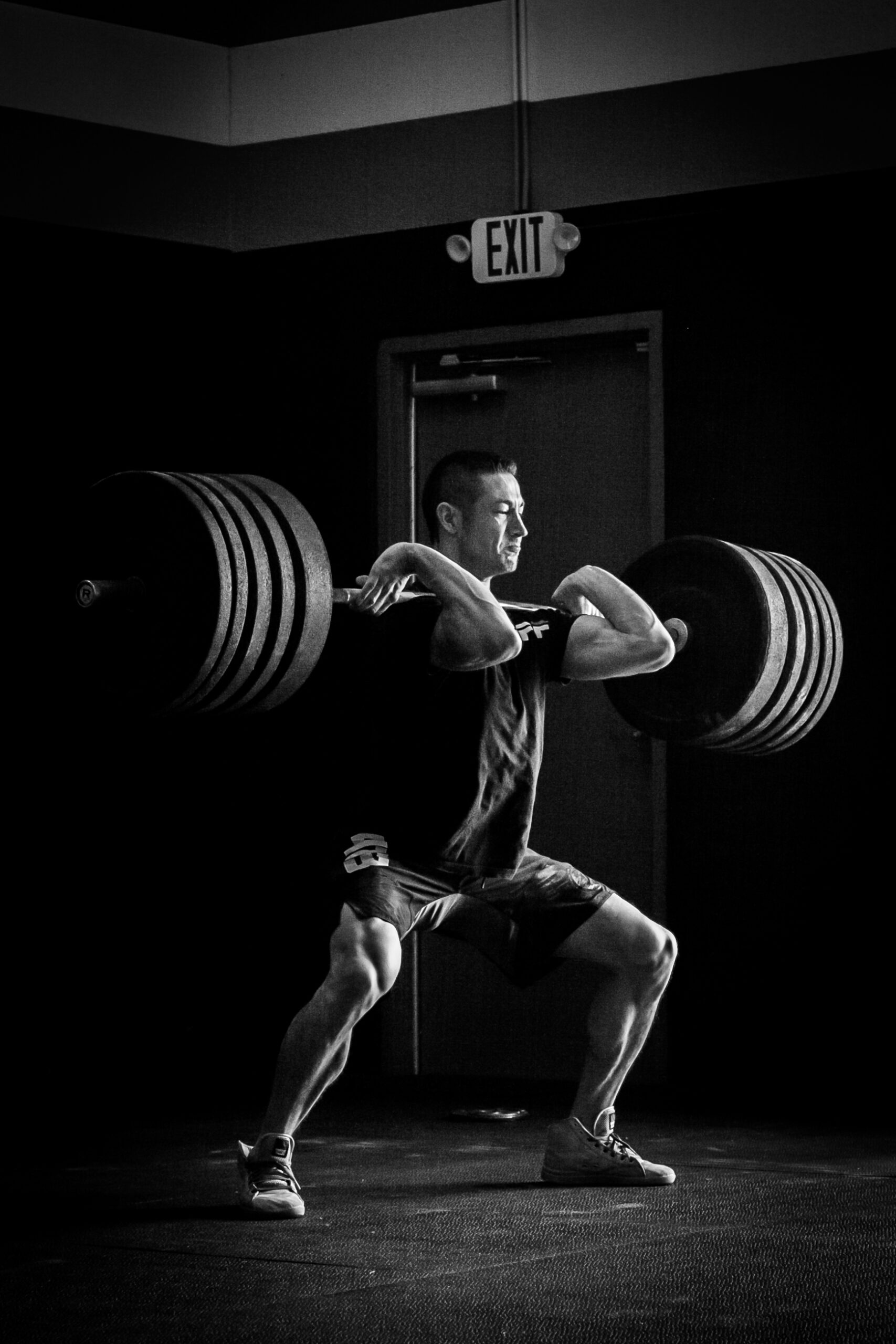 Focused Man Performing a Heavy Barbell Squat in a Gym