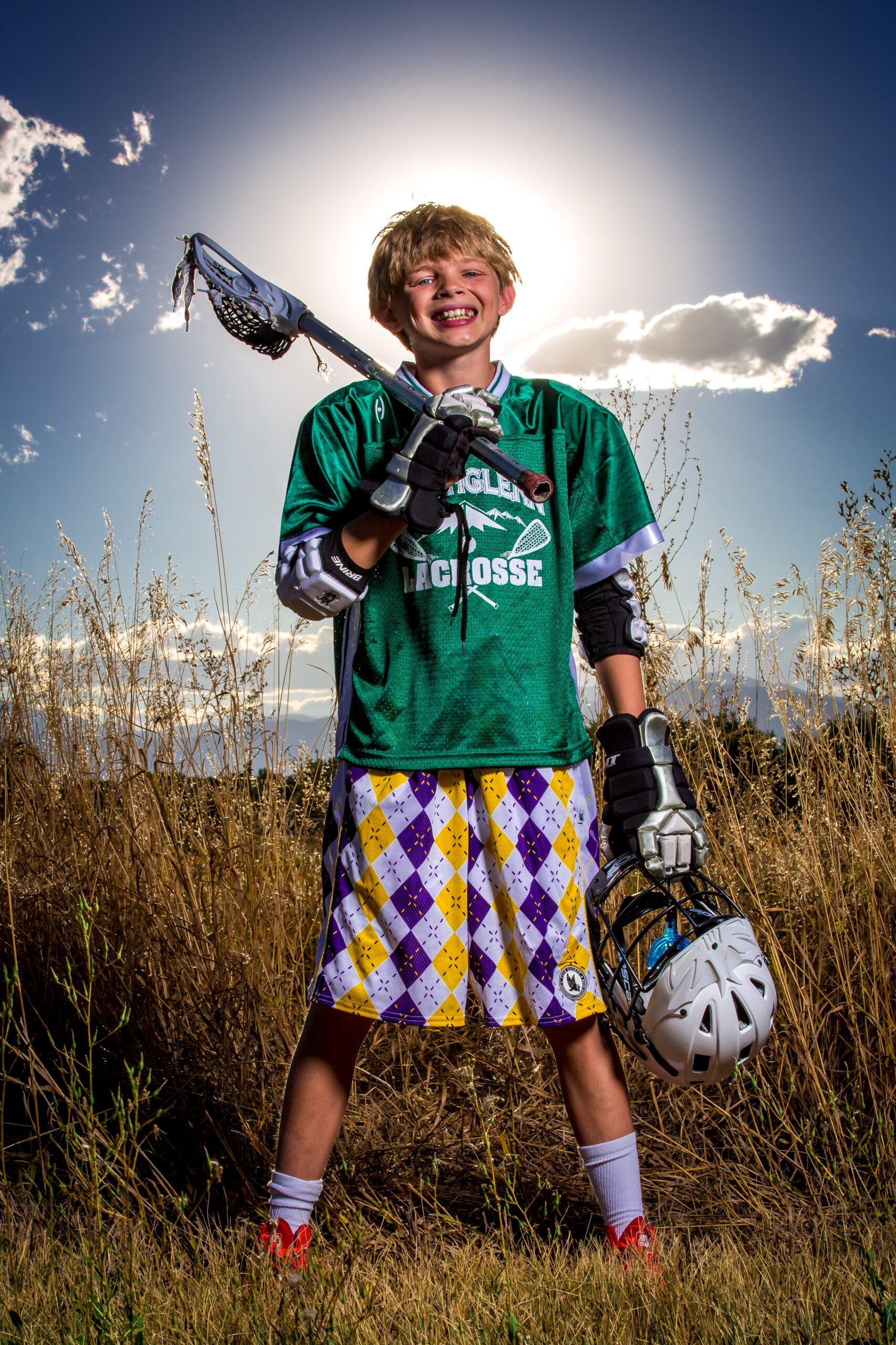 Young Lacrosse Player Smiling in Field With Sun Halo Effect