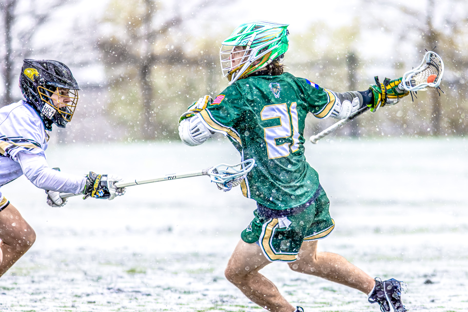Mountain Vista Lacrosse team playing in the snow, showcasing dynamic action and vibrant metallic green helmets.