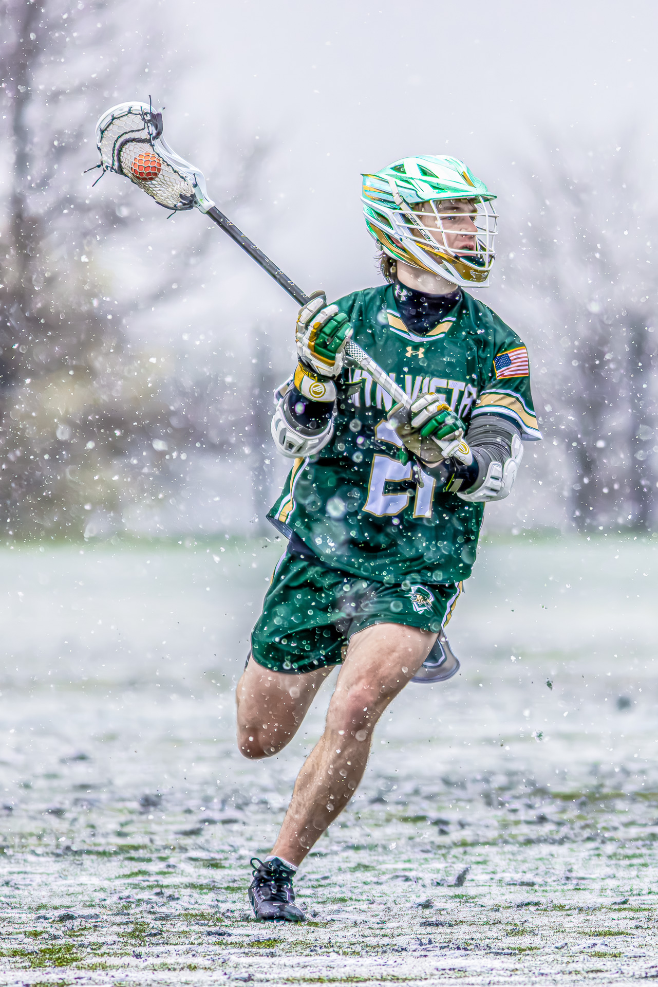 Mountain Vista Lacrosse team playing in the snow, showcasing dynamic action and vibrant metallic green helmets.