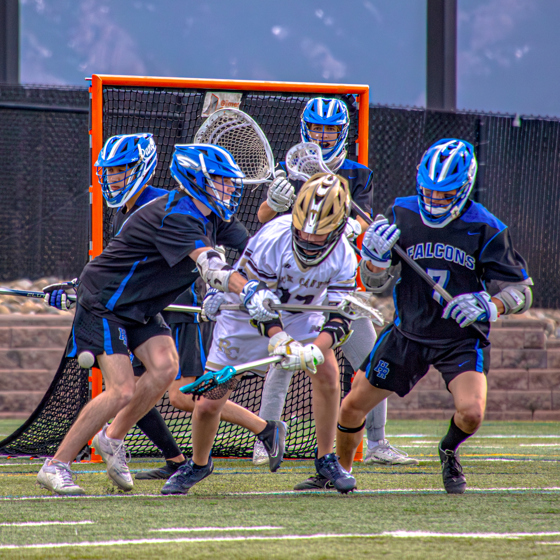 Highlands Ranch High School lacrosse team defense encircling a Rock Canyon player during a springtime game in Colorado.