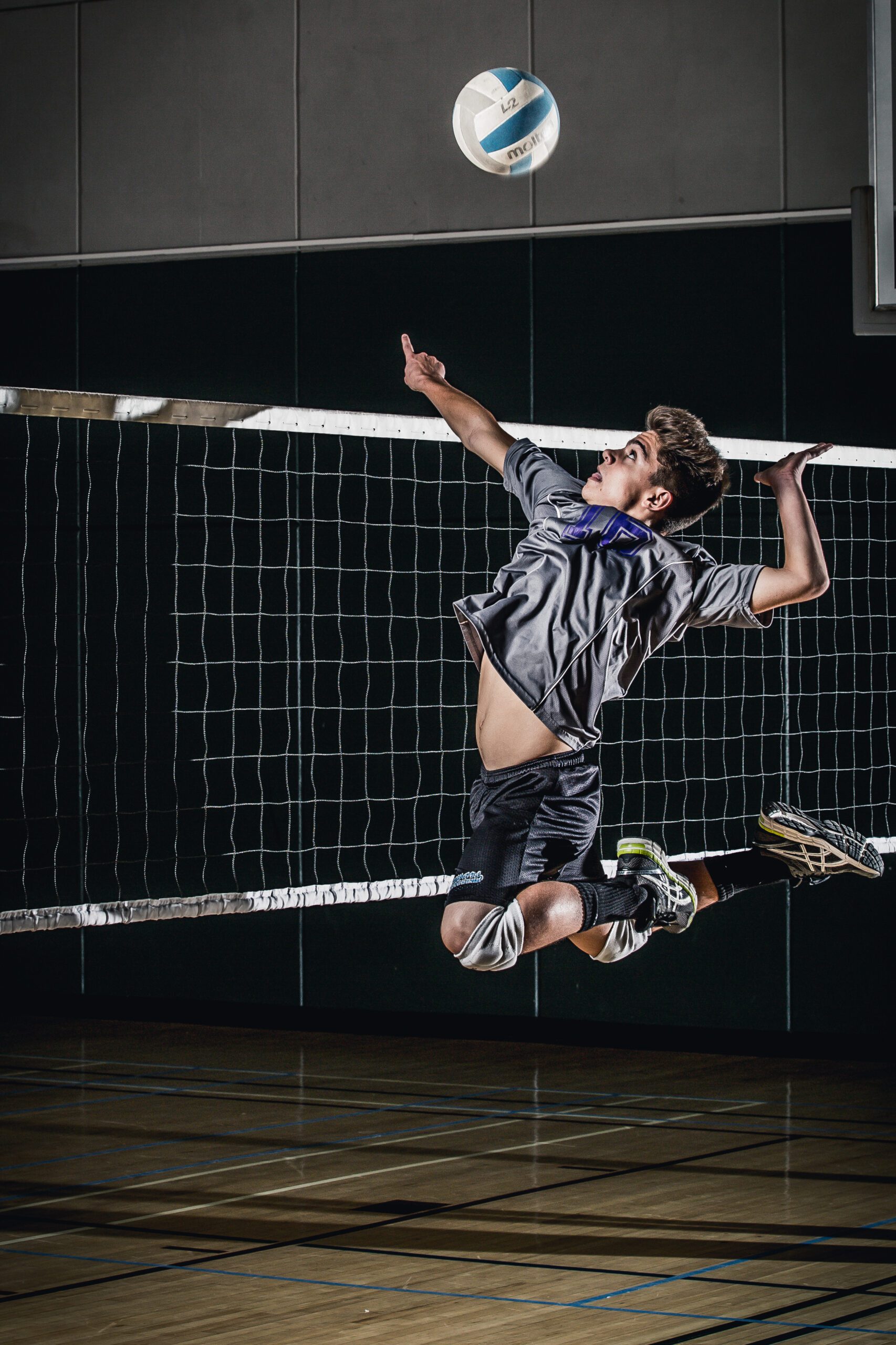 Male Volleyball Player Leaping for a One-Handed Save in an Indoor Court
